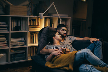 couple with applied cosmetic face mask relaxing at home. evening scene