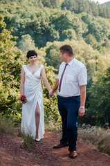 Newlyweds hold hands on the background of the forest