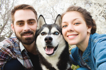 happy smiling couple with husky dog