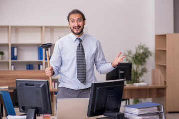 Young male employee holding plunger in funny concept