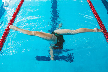 synchronized swimming athlete trains alone in the swimming pool. Training in the water upside down. Legs peek out of the water. sports figure from legs