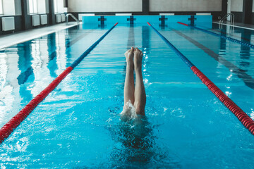 synchronized swimming athlete trains alone in the swimming pool. Training in the water upside down. Legs peek out of the water. sports figure from legs