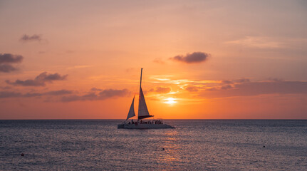 sunset at eagle beach in aruba in the caribbean with catamaran in composition