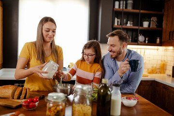 Mom, dad and daughter are cooking in kitchen. Man, young woman and little daughter are making lunch.