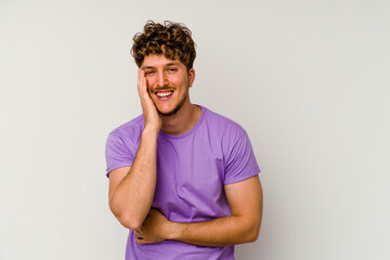 Young caucasian man isolated on white background laughs happily and has fun keeping hands on stomach.