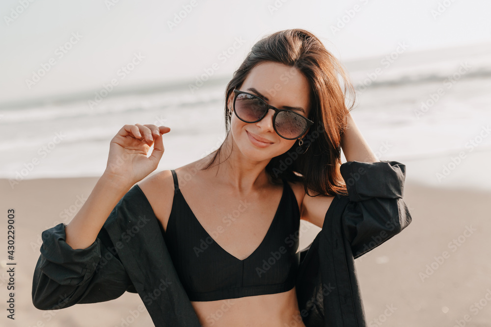 Wall mural pretty young woman having fun on vacation, smiling, looking to side. wearing stylish sunglasses and 