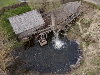 Water mill wheel rotates under a stream of water. Traditional village machinery, aerial view © Chepko Danil