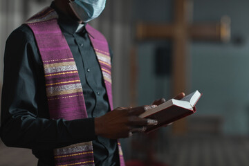Close-up of priest in costume reading the Bible while standing at the altar during ceremony
