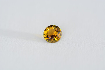 Genuine natural round custom cut faceted brown yellow color loose clean transparent tourmaline gemstone setting for making jewelry. Side daylight on white paper background.