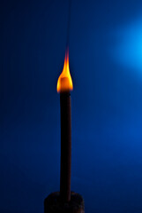 burning candle on blue background