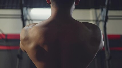 Rear view shot of male athlete doing exercise by suspension training.