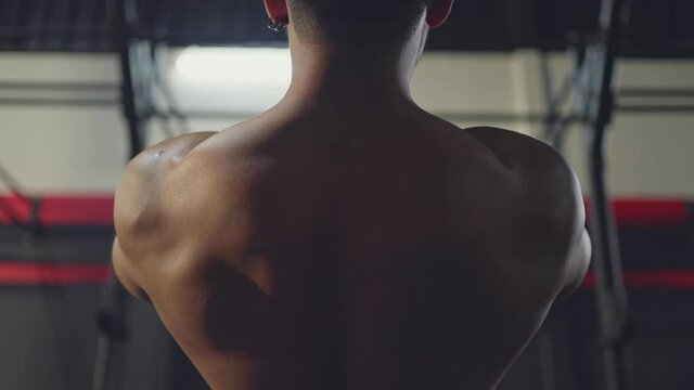 Rear view shot of male athlete doing exercise by suspension training.