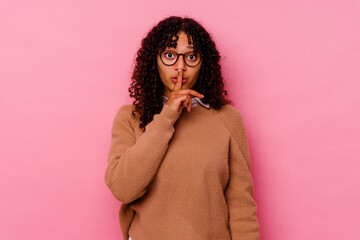 Young mixed race woman isolated on pink background keeping a secret or asking for silence.