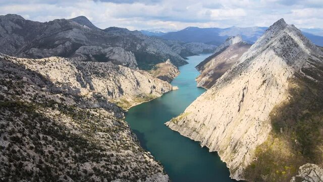 Aerial view of a beautiful landscape of mountain lake in Riano Castilla y Leon, Spain. Emerald water surrounded by mountains and passing clouds. High quality 4k footage