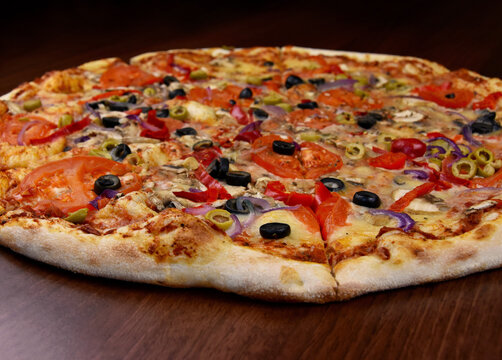 Whole delicious vegetarian pizza stock images. Veggie pizza with tomatoes, cheese, olives, mushrooms and peppers on the table stock photo. Vegetable pizza without meat close-up images