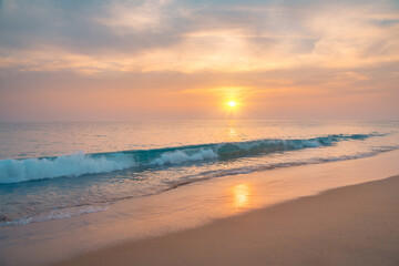 Fototapeta na wymiar Waves on the sandy ocean beach under a beautiful sunset sky with clouds on Sri Lanka island.