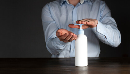 Hands of a male businessman in a shirt use a dispenser with an antiseptic against viruses. The concept of the fight against coronavirus.