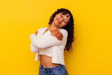Young mixed race woman isolated on yellow background hugs, smiling carefree and happy.