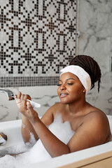 Side view on careful african woman doing manicure in bathtub at home