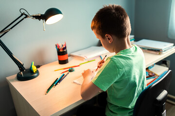 Boy sitting at the desk doing homework at home.