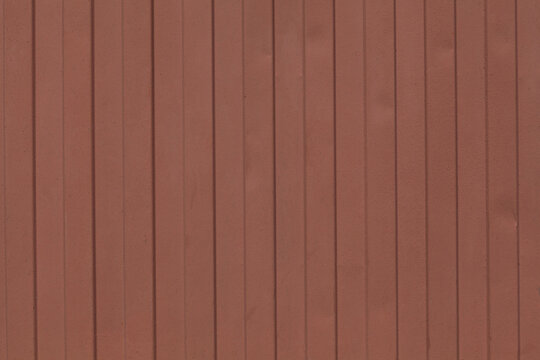Surface of metal fence with grooved vertical stripes. Rough texture with defects and dents, colored brown. Design element
