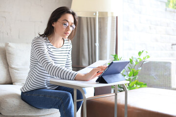 Smiling girl sit on couch watching webinar on laptop. Happy young woman study on online distant course.