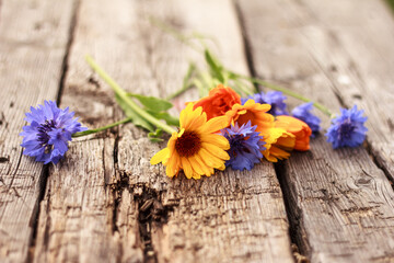 Beautiful  blue cornflowers and calendula lay on rough wooden board. Bright summer bouquet. Summer background