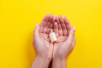 Woman hands holding a bottle with homeopathic pills on white background .