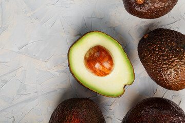 Sliced and whole organic Hass avocado on a gray background.