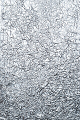 Crumpled shiny metal foil texture or background for design. Gradient, cool shades. Abstract drawing on a thin sheet of aluminum foil. Vertical photo