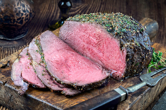 Traditional barbecue dry aged angus roast beef steak with Yorkshire pudding and herbs served as close-up on a rustic wooden board