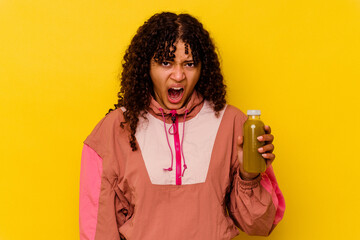 Young mixed race sport woman holding a smoothie isolated on yellow background