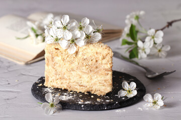 a piece of cake Napoleon and spring flowers is on the table