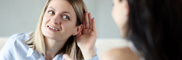 Young woman holding her ear and talking to friend