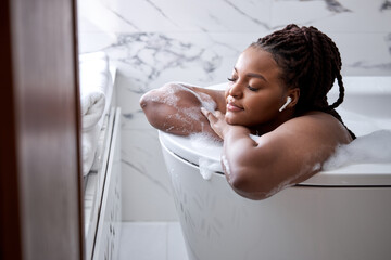 Luxury bath african woman relaxing in hotel spa bathtub or home bathroom for total relaxation