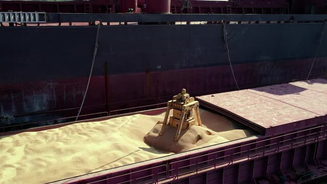 Areal barge hold with soybean, grain or wheat on underway ship to ship transfer operation of bulk commodities open sea. Gantry crane lift and load dry freight on merchant vessel. Ocean transportation