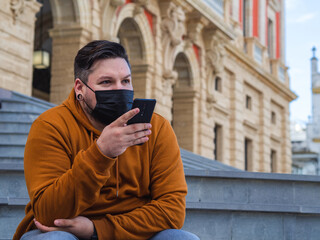 Hombre joven usando su móvil con mascarilla durante la pandemia del coronavirus