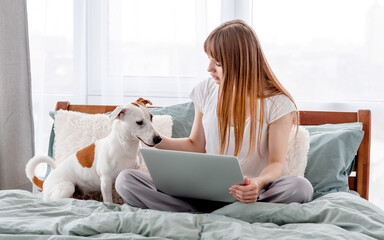 Girl with dog and laptop in the bed