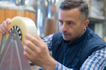 worker fitting roll of tape on production line