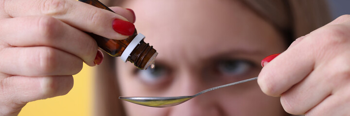 Woman dripping drops from medicine bottle closeup