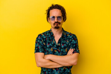 Young caucasian man wearing summer clothes isolated on yellow background frowning face in displeasure, keeps arms folded.