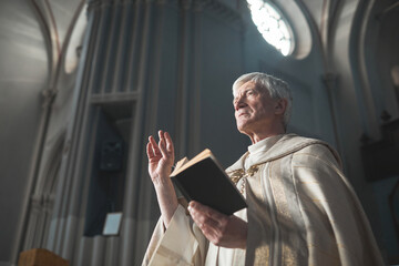 Senior man in costume reading the Bible while serving in the church