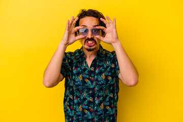 Young caucasian man wearing summer clothes isolated on yellow background keeping eyes opened to find a success opportunity.