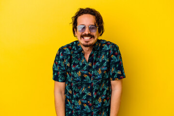 Young caucasian man wearing summer clothes isolated on yellow background laughs and closes eyes, feels relaxed and happy.