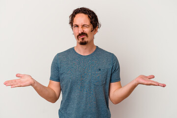 Young caucasian man isolated on white background doubting and shrugging shoulders in questioning...