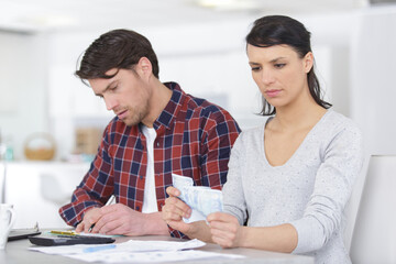 couple embracing and calculating the bills at home