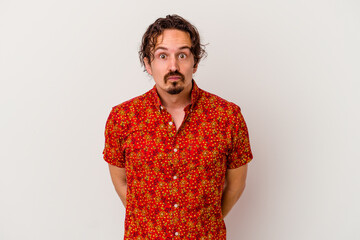 Young caucasian man isolated on white background shrugs shoulders and open eyes confused.