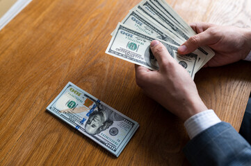 Male hands counting US Dollar bills or paying in cash on money background. Concept of investment,...