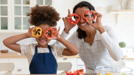 Happy excited mommy and daughter girl having fun while cooking in kitchen. Funny mom and kid making...