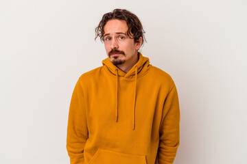Young caucasian man isolated on white background shrugs shoulders and open eyes confused.
